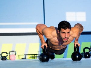 Gym man push-up strength pushup exercise with Kettlebell in a wo